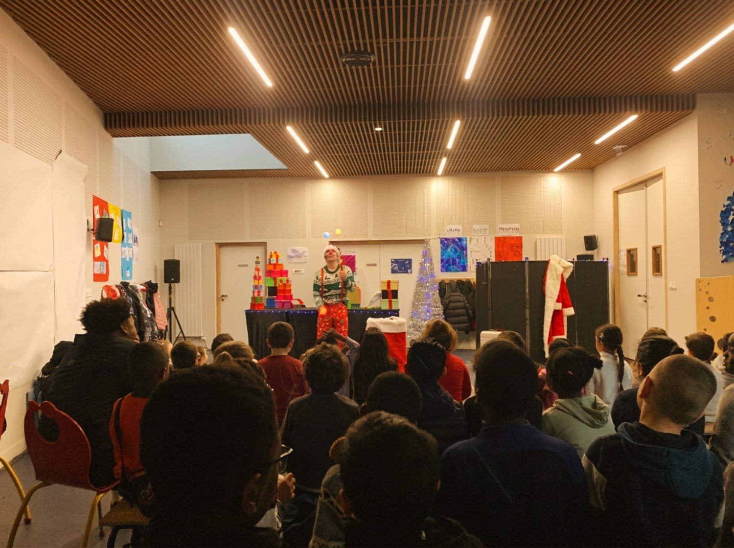 Une classe entière assise face à Félix, dans une salle polyvalente.